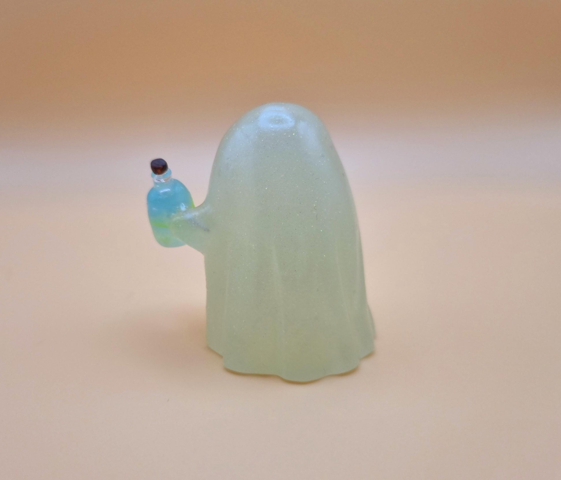 Cute night glow ghost with little blue and green poison bottle with skull on it on orange background back view